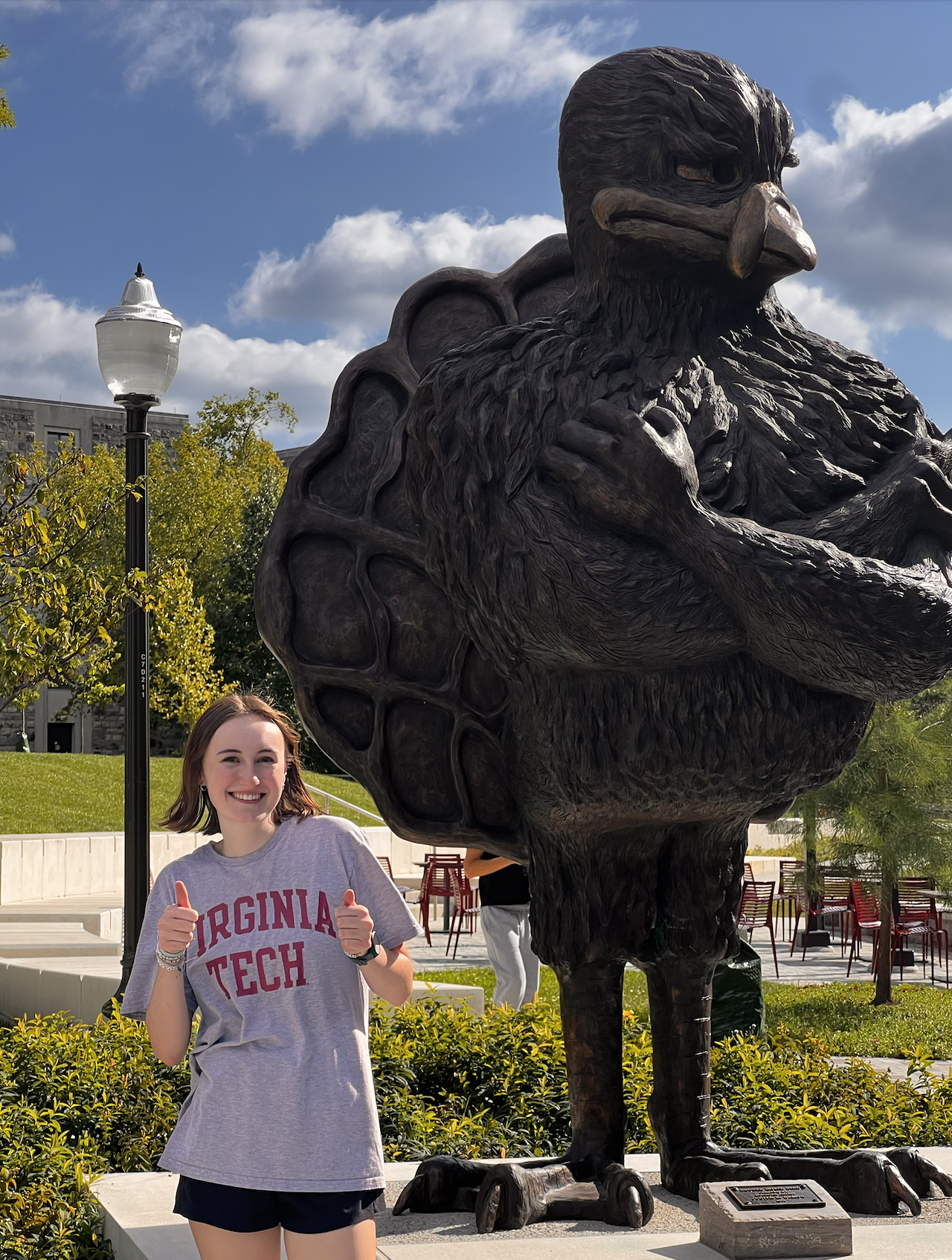 a woman posing in front of a statue of a bird